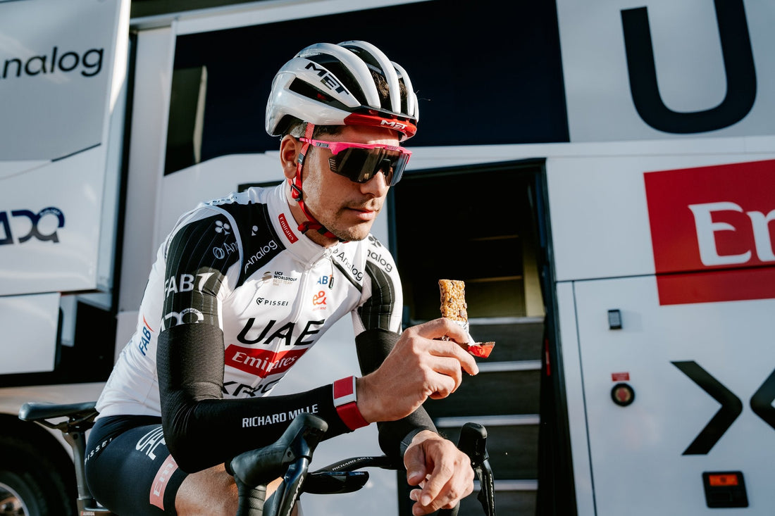 Cyklista UAE Team Emirates XRG s energetickou tyčinkou u týmového autobusu
