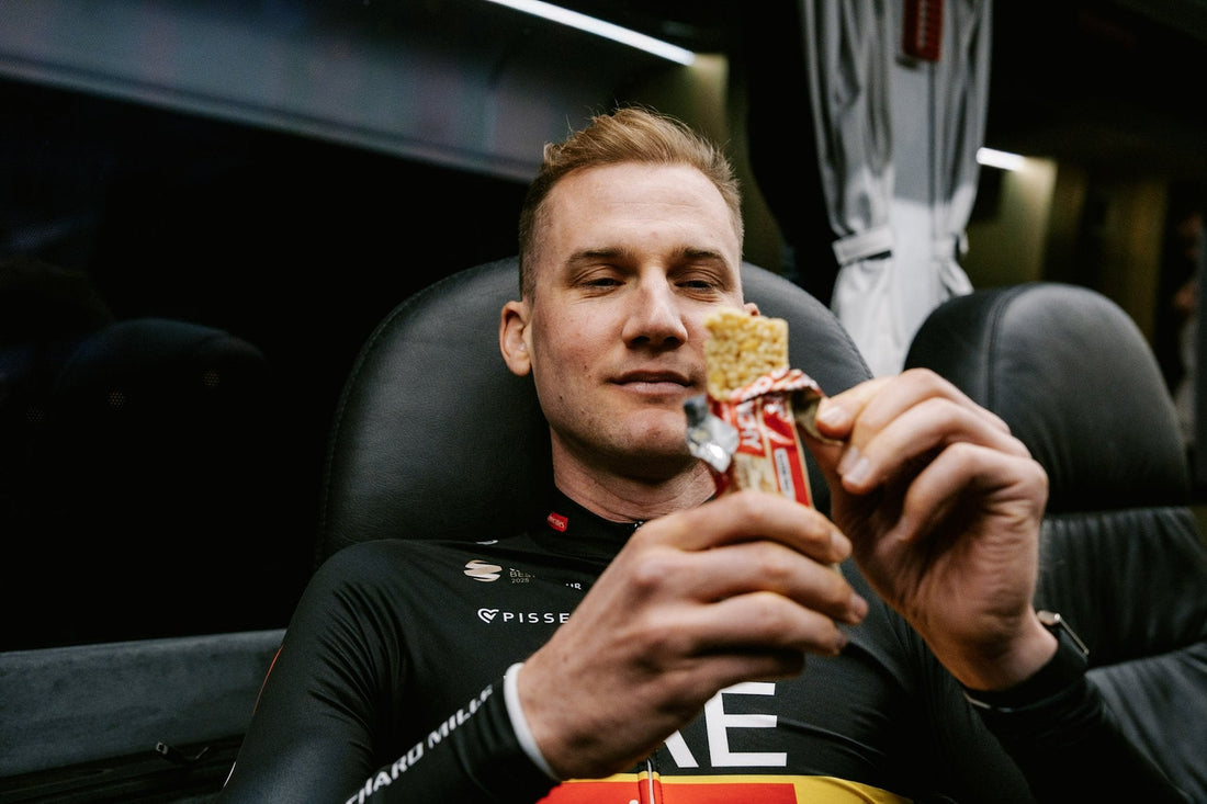 Cyklista UAE Team Emirates XRG jí tyčinku ENERVIT Power Crunchy